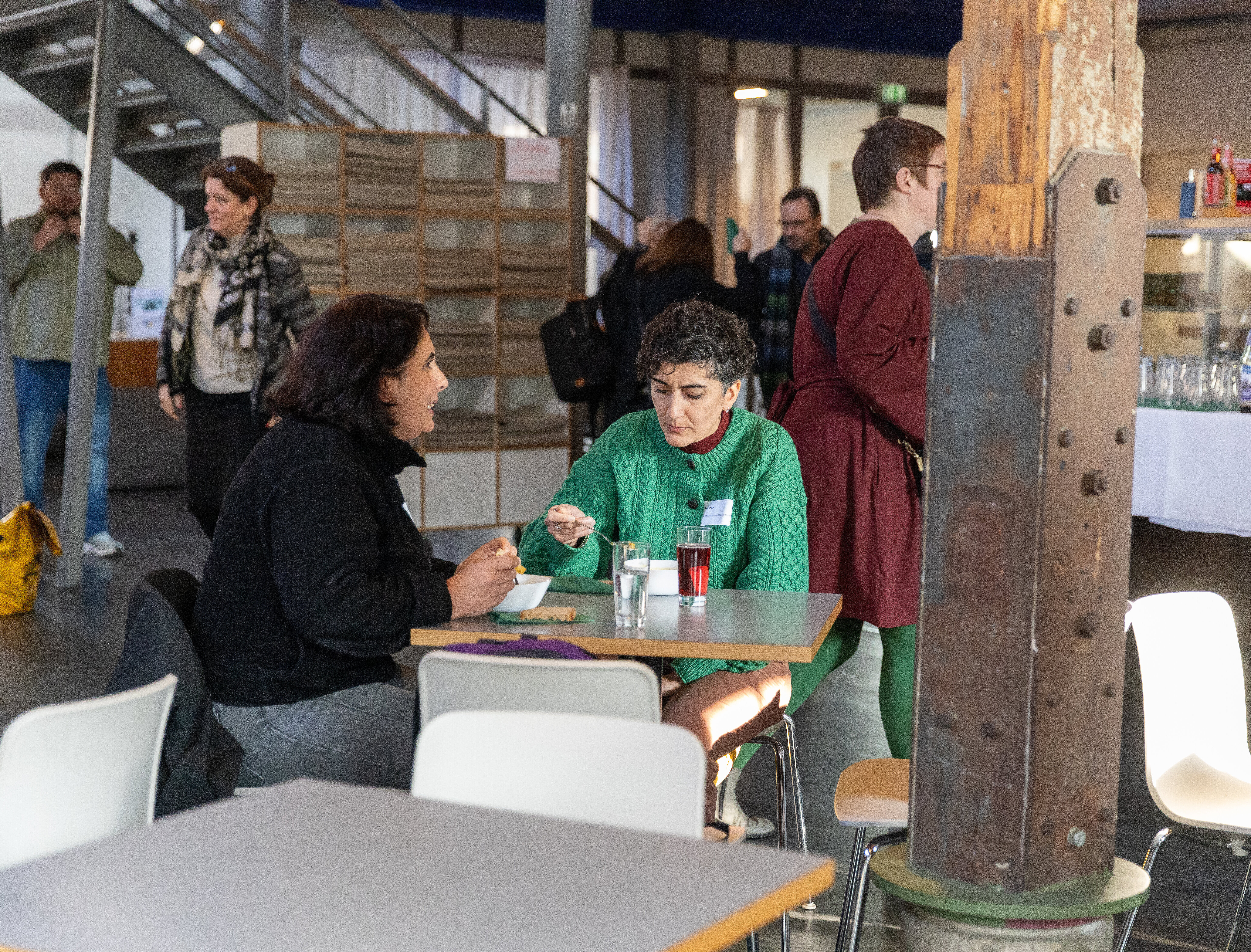 Zwei Personen sitzen am Tisch, essen Suppe und unterhalten sich