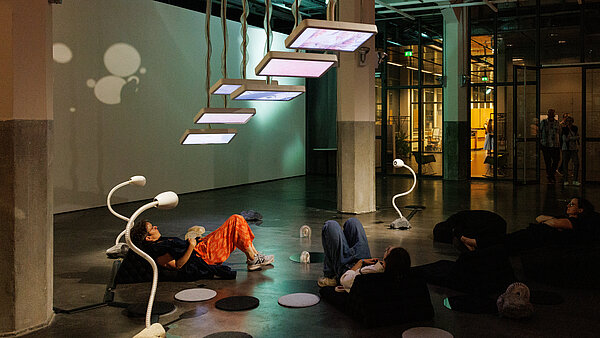 Menschen auf Sitzsäcken, die Bildschirme an der Decke betrachten