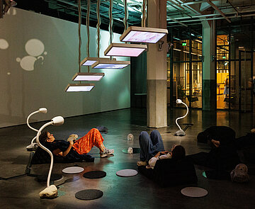 Menschen auf Sitzsäcken, die Bildschirme an der Decke betrachten