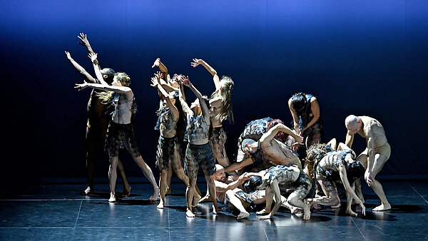 Tänzer performen auf einer blau ausgeleuchteten Bühne