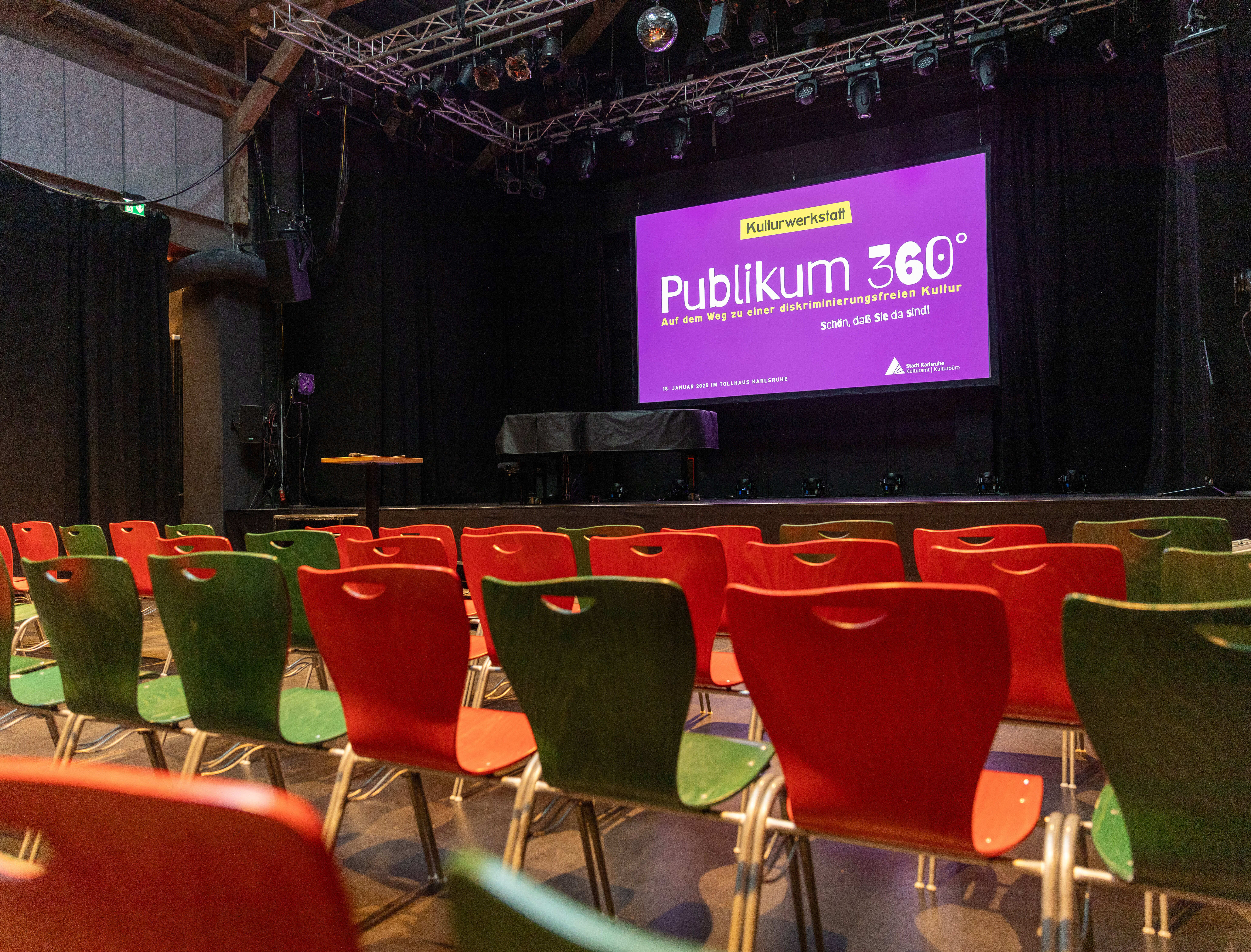 Blick aus dem Zuschauerraum auf eine Bühne mit Leinwand und Präsentation der Kulturwerkstatt