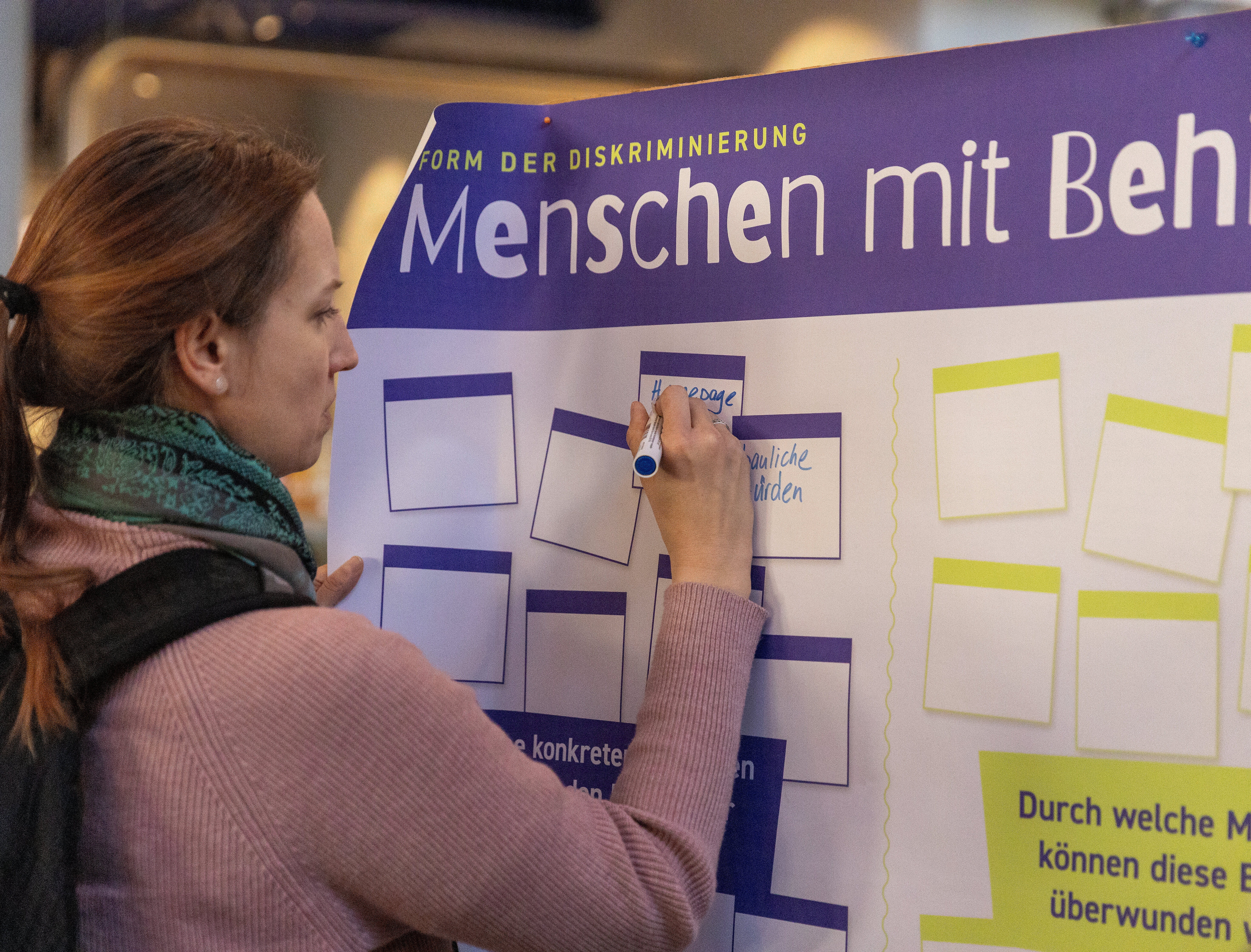Teilnehmende Person schreibt etwas auf ein Plakat