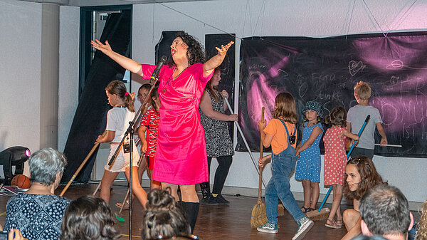 Singende Frau mit Kindern auf einer Bühne