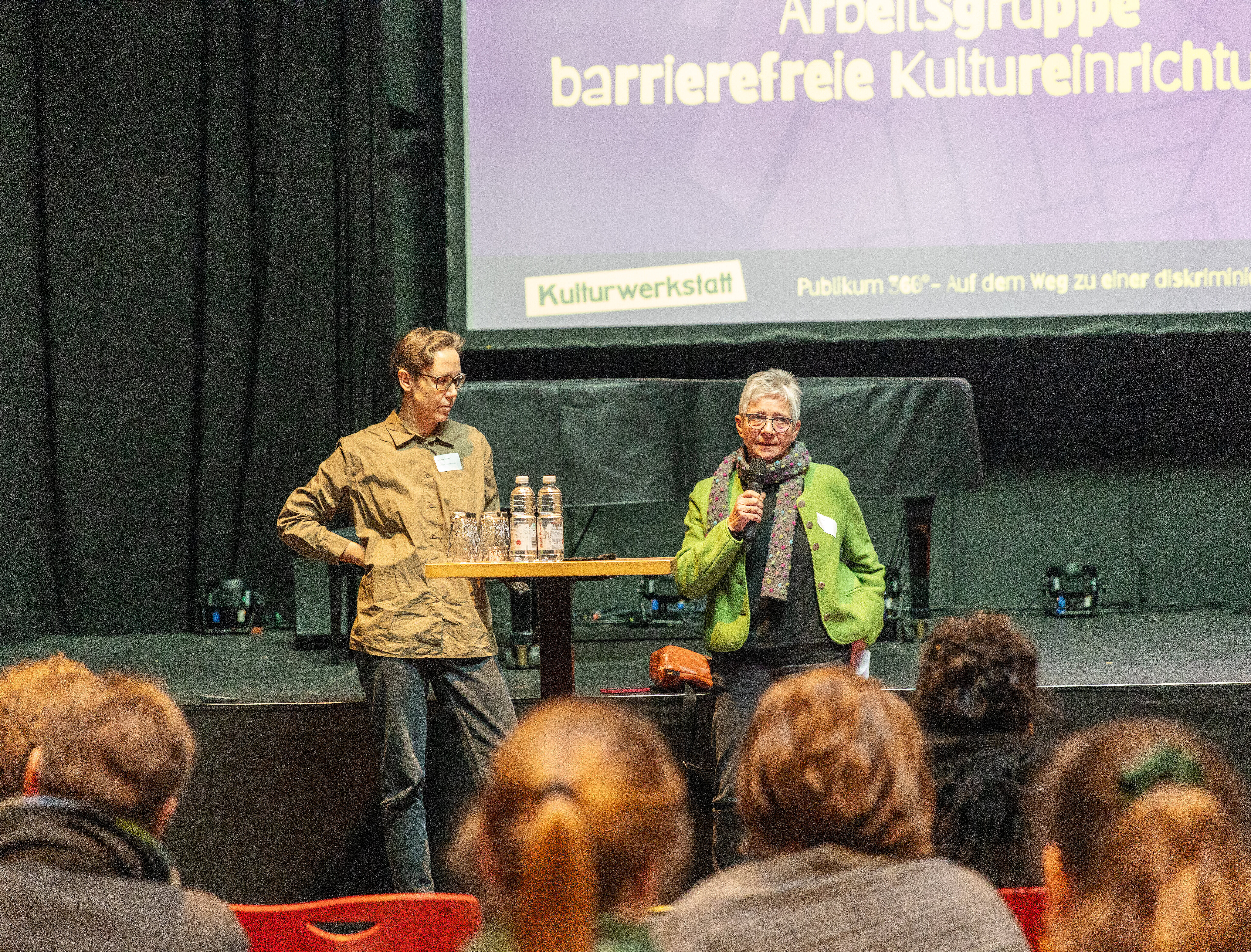 Zwei Speaker auf der Bühne halten einen Vortrag vor Publikum